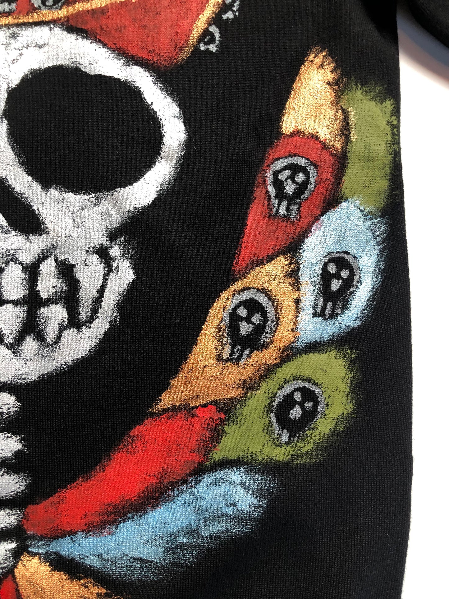 Details of hand-painted skull with wings paints on women's clothing. Women's blouse Winged skull in a hat