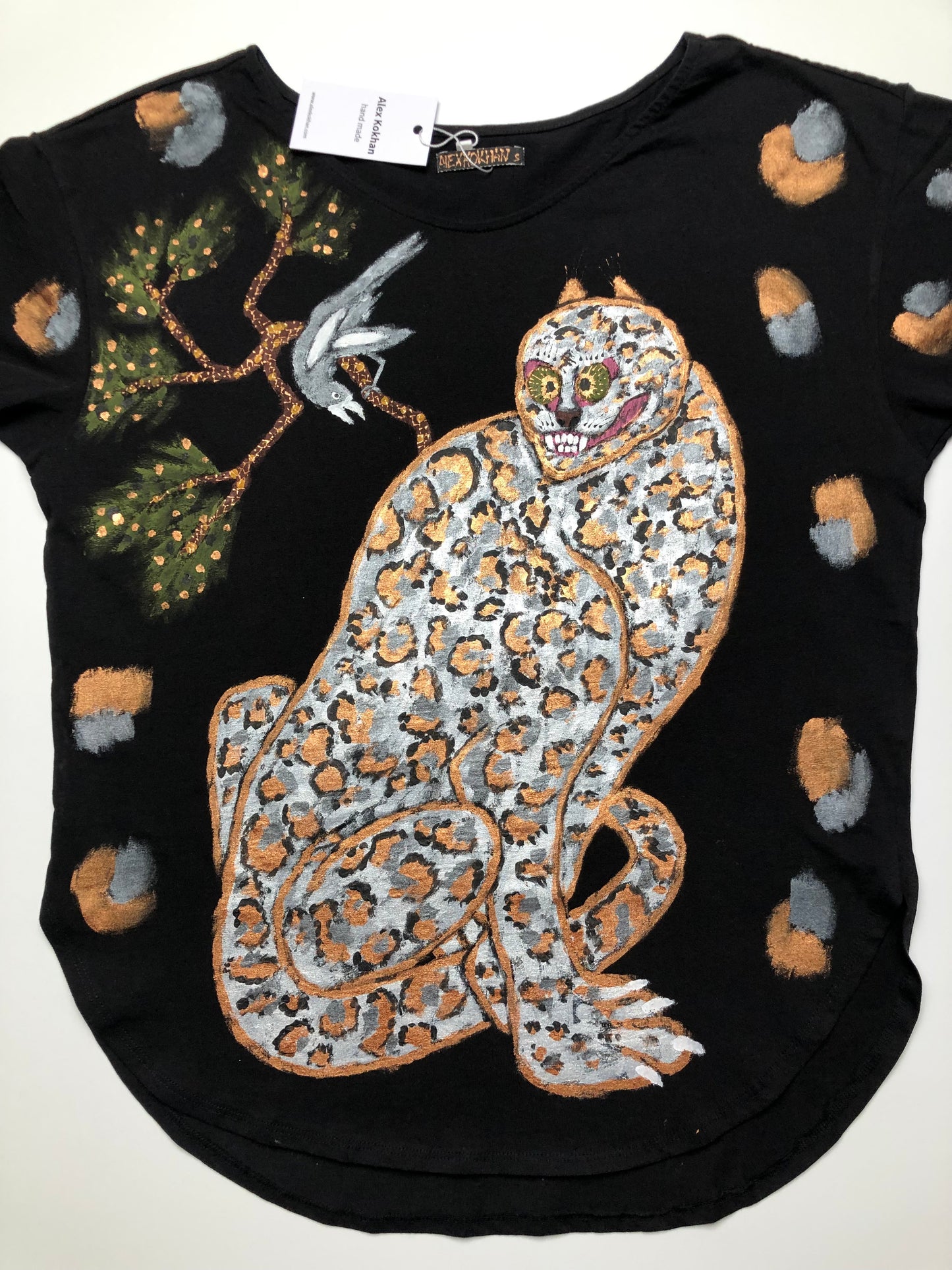 The front side of a handmade black women's T-shirt with a leopard and a bird on a tree