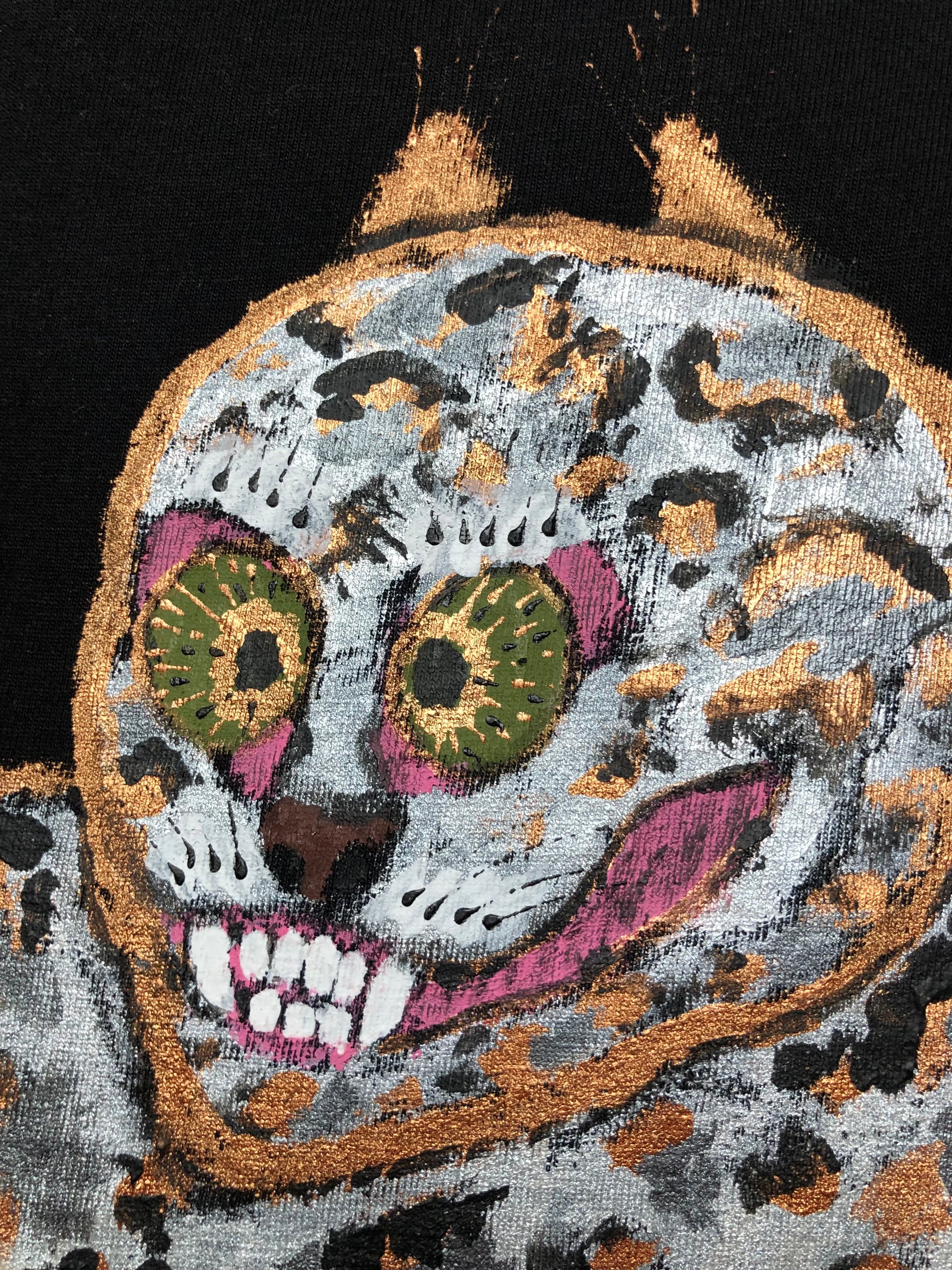 Very detailed muzzle of a leopard with mustaches, fangs and olive eyes on the surface of a black t-shirt