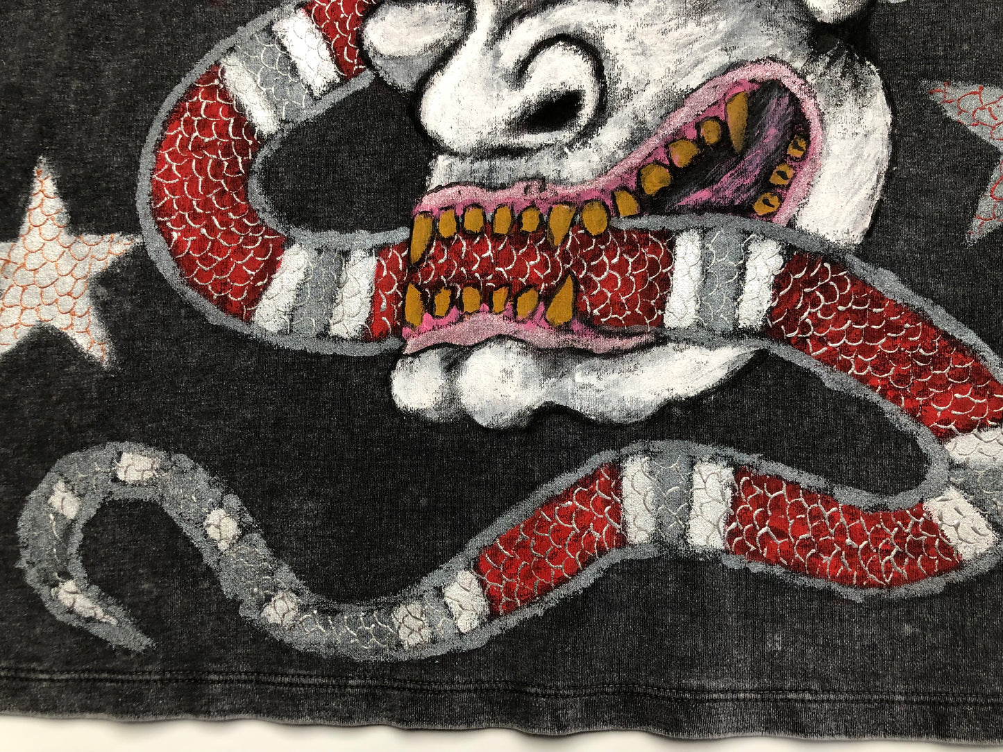 The bottom of the t-shirt with a demon and a snake