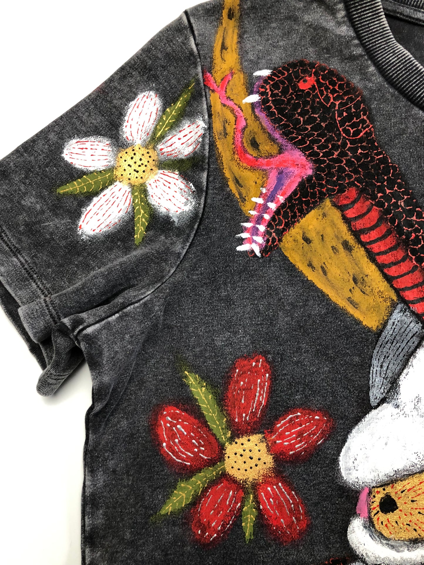 In detail the sleeve of a T -shirt with a snake and a floral design