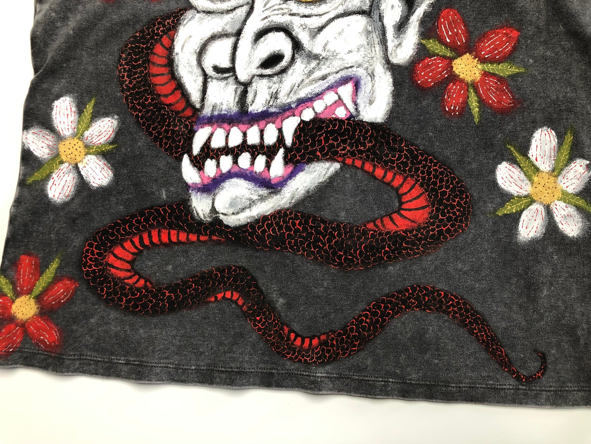The lower part of the T -shirt with a demon, snake and floral design